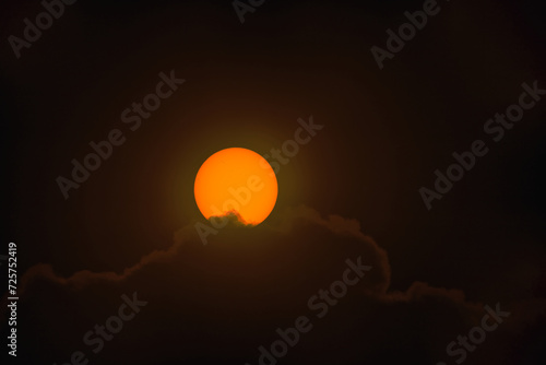Tarcza słoneczna sfotografowana z użyciem teleobiektywu. W wyniku zastosowania filtra optycznego uzyskano ciepłą barwę tarczy słonecznej. Widoczne są plamy na powierzchni słońca. 