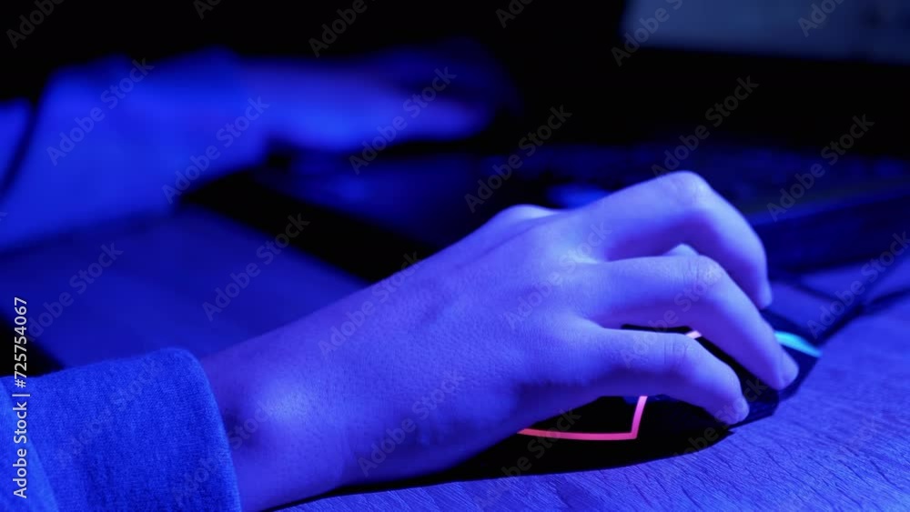 Hands of Gamer Playing Video Game at Computer in a Virtual Room at Night. Close up. Typing on the keyboard. Online eSports competition. Neon backlight, keyboard, computer mouse. Hacker or freelancer. Hands of Gamer Playing Video Game at Computer in a Virtual Room at Night. Close up. Typing on the keyboard. Online eSports competition. Neon backlight, keyboard, computer mouse. Hacker or freelancer.