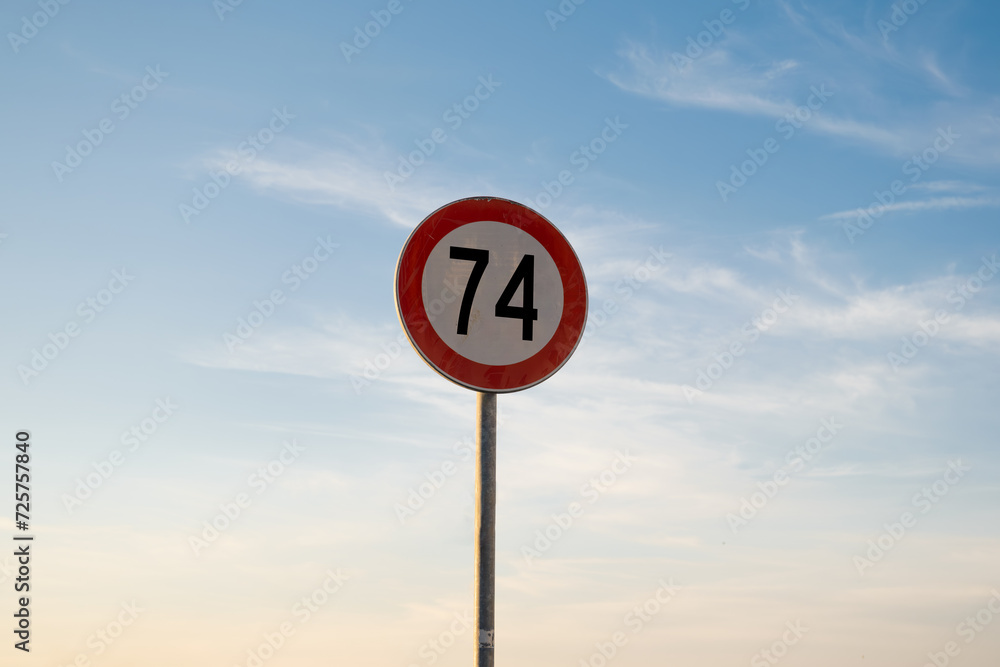 74 miles km maximum speed limit traffic sign isolated with sunset sky 74 miles km maximum speed limit traffic sign isolated with sunset sky