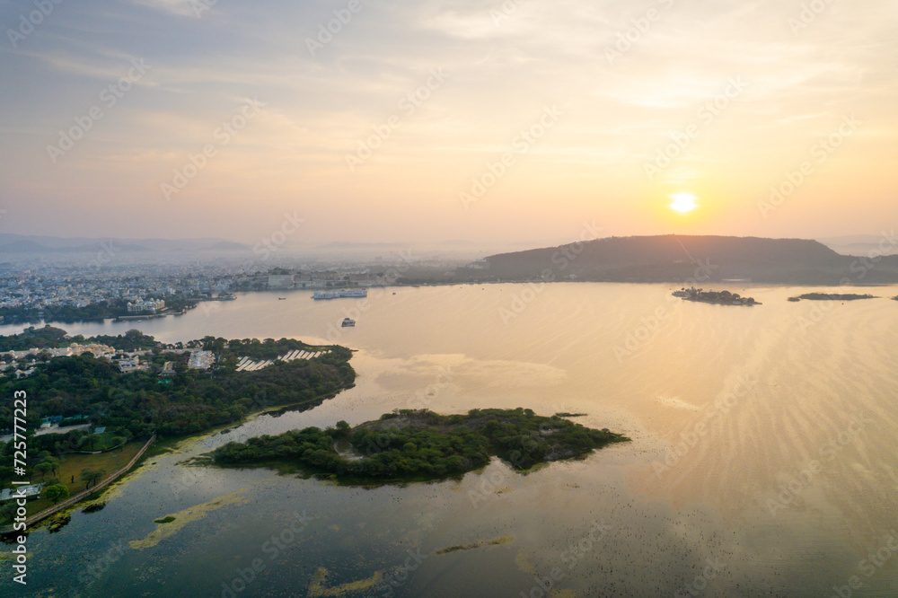 Aerial drone shot dawn dusk cityscape of Udiapur Rajasthan India with blue pink purple water of lake pichola fateh sagar towards aravalli mountains on foggy morning