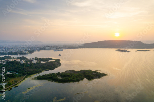 Aerial drone shot dawn dusk cityscape of Udiapur Rajasthan India with blue pink purple water of lake pichola fateh sagar towards aravalli mountains on foggy morning