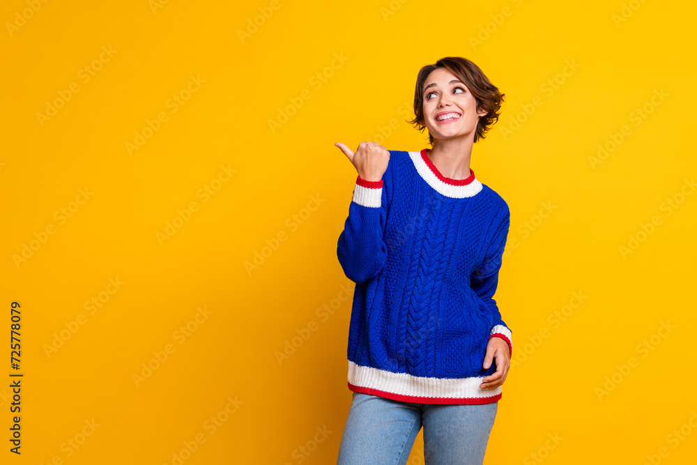 Photo portrait of pretty young girl point look cheerful empty space dressed stylish blue knitted outfit isolated on yellow color background Photo portrait of pretty young girl point look cheerful empty space dressed stylish blue knitted outfit isolated on yellow color background