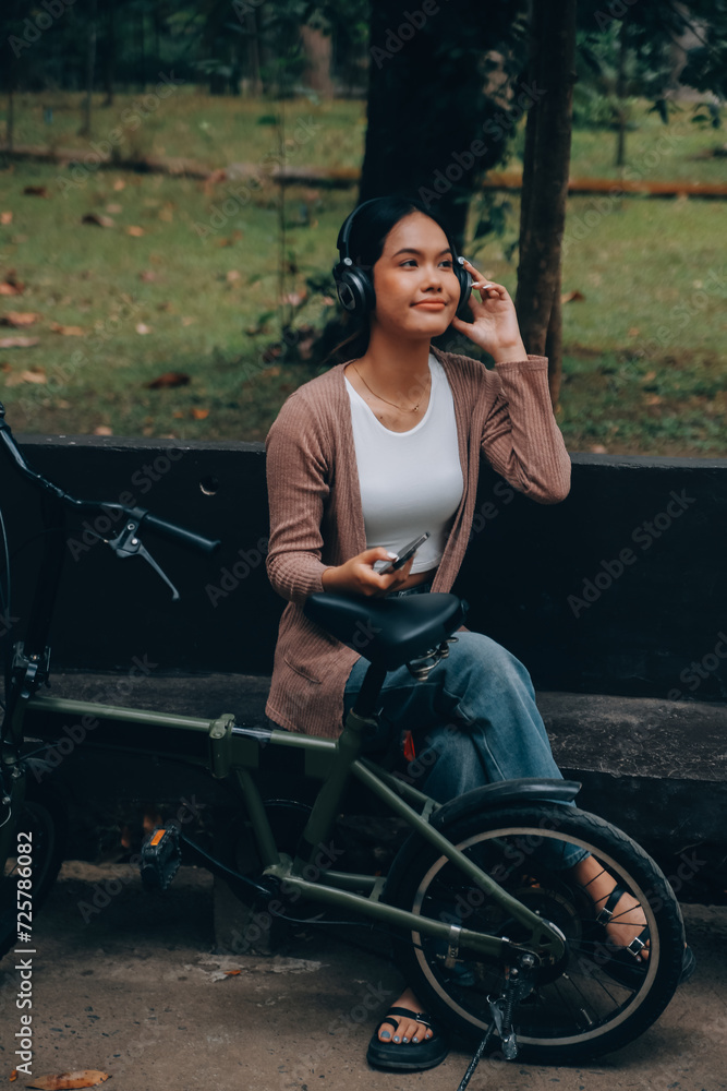Happy young Asian woman while riding a bicycle in a city park. She smiled using the bicycle of transportation. Environmentally friendly concept. Happy young Asian woman while riding a bicycle in a city park. She smiled using the bicycle of transportation. Environmentally friendly concept.