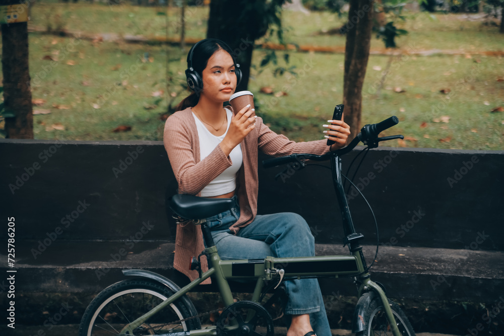 Happy young Asian woman while riding a bicycle in a city park. She smiled using the bicycle of transportation. Environmentally friendly concept.