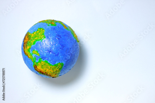 Planet earth on a light blue background. Toy model of the globe. World ecology and environmental problems. Top view, place for text.