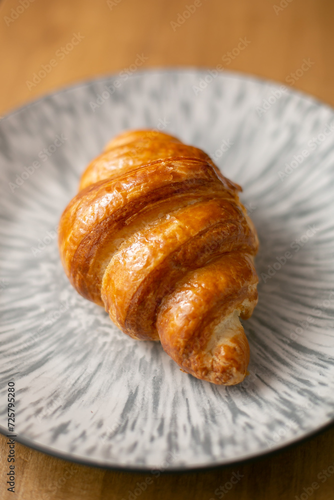 Croissant on a grey plate on a wooden background