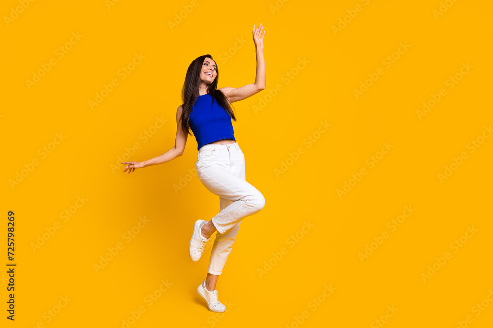 Full length photo of cute carefree woman wear blue top dancing having fun empty space isolated yellow color background
