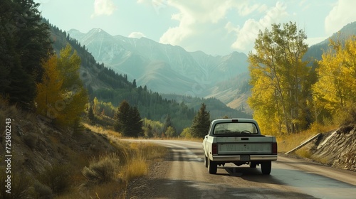 A pickup truck with a snorkel drives on a scenic road surrounded by mountains and trees
