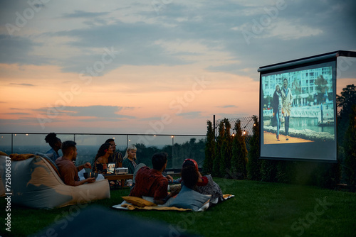 Group of friends enjoying in movie night on patio.