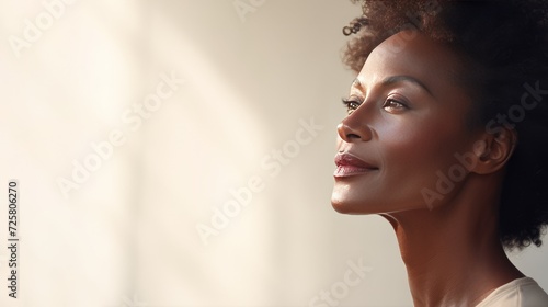 portrait of a beautiful middle-aged dark-skinned woman with natural makeup on a neutral background with space for text. The concept of natural beauty and anti-aging skin care photo