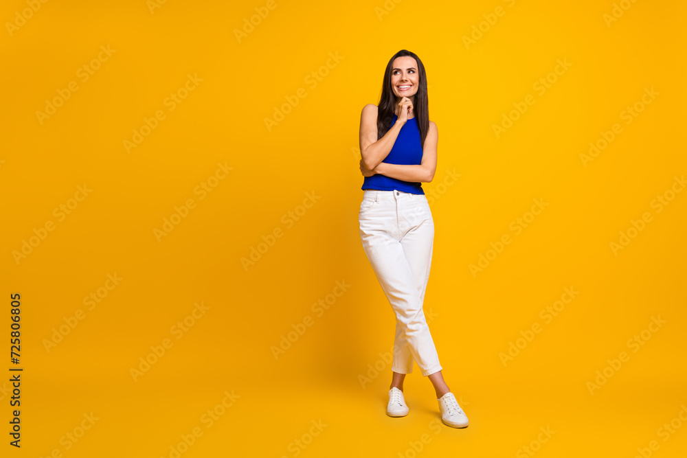 Full length photo of good mood thoughtful lady dressed blue top arm chin looking empty space isolated yellow color background Full length photo of good mood thoughtful lady dressed blue top arm chin looking empty space isolated yellow color background