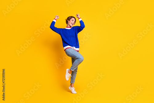 Full length photo of excited lucky lady dressed knitted sweater rising fists screaming yes empty space isolated yellow color background