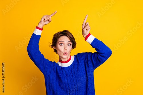 Photo portrait of attractive young woman point shocked empty space wear trendy blue knitwear clothes isolated on yellow color background photo
