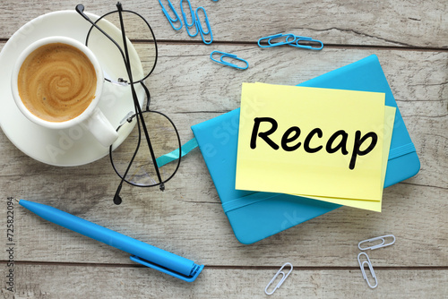 top view of a cup of coffee and glasses. blue notepad and text on paper Recap