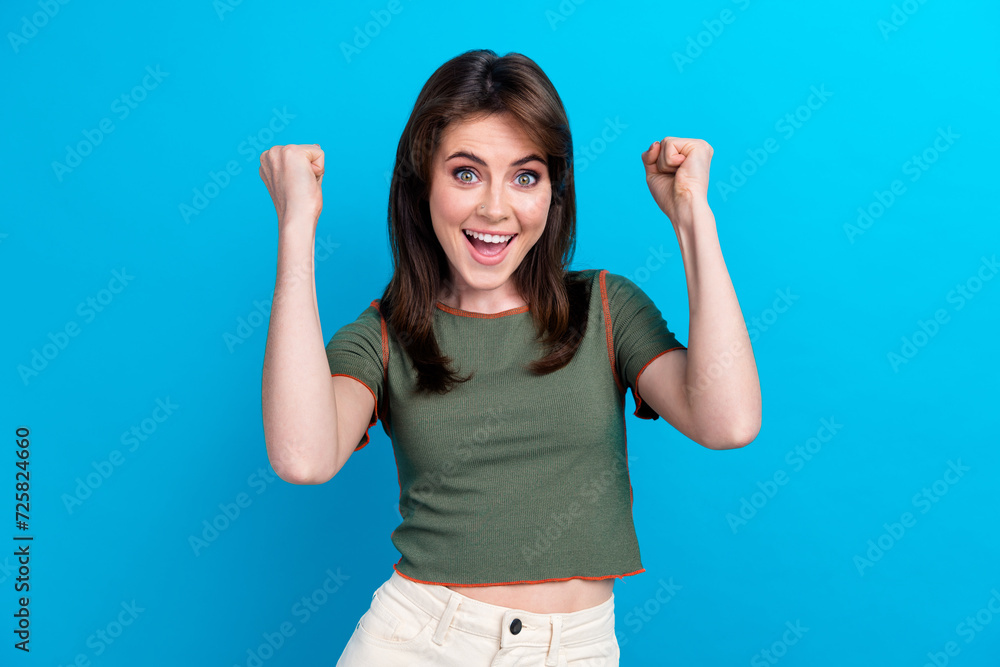 Fototapeta premium Photo of delighted cheerful girl raise fists yes achievement accomplishment isolated on blue color background