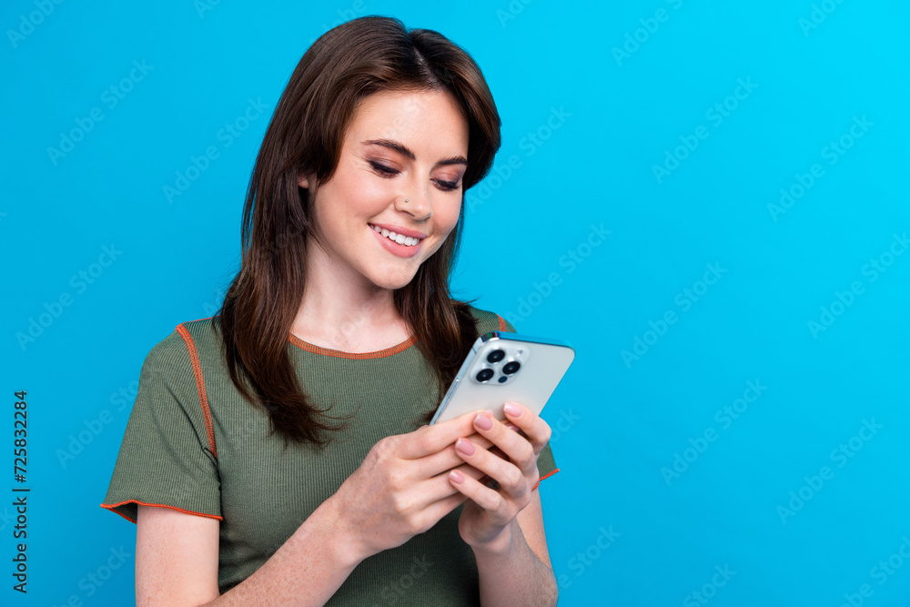 Photo of pretty lovely person use smart phone write blog post empty space isolated on blue color background Photo of pretty lovely person use smart phone write blog post empty space isolated on blue color background