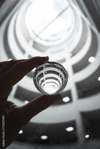 Canvas Print Hand cradles a crystal ball, revealing a modern leaf-shaped skylight atop a sleek white architectural structure
