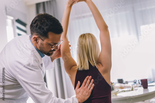 Chiropractor treating a young woman as a patient in his office.