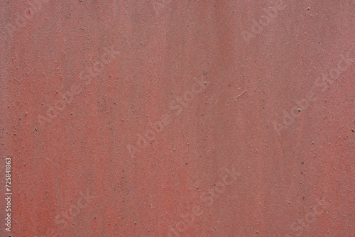 An old, uneven, metal surface with bumps covered with brown, red, cherry paint. Rough brown, metallic background.