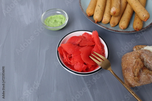 Red ginger in a plate with bread meat on a gray background with space for text. Sandwich recipe. Application of sauces
