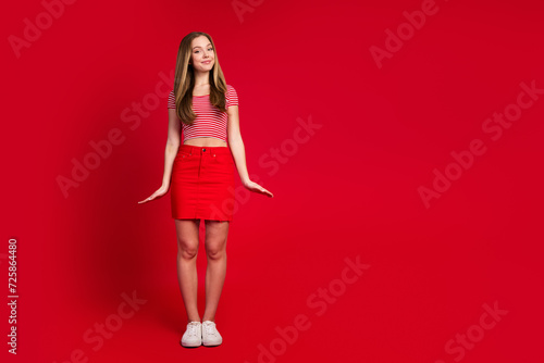 Full length photo of good mood sweet lady dressed striped top mini skirt empty space isolated red color background