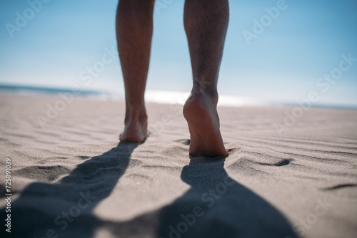 Men's bare feet on the sand. Close-up of the legs.