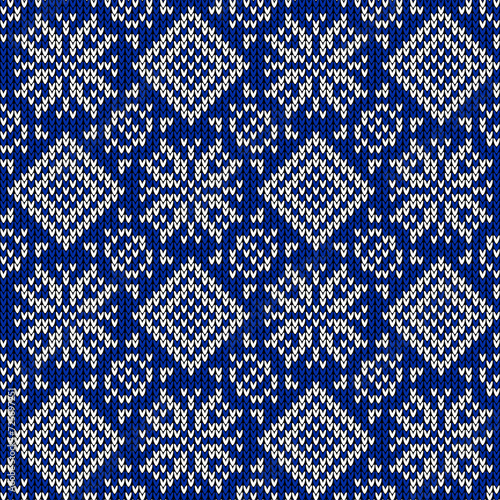 Knitted seamless pattern with white ornament and blue background. Fashionable northern stylish design. Knitted style. Creative illustration with winter motive.