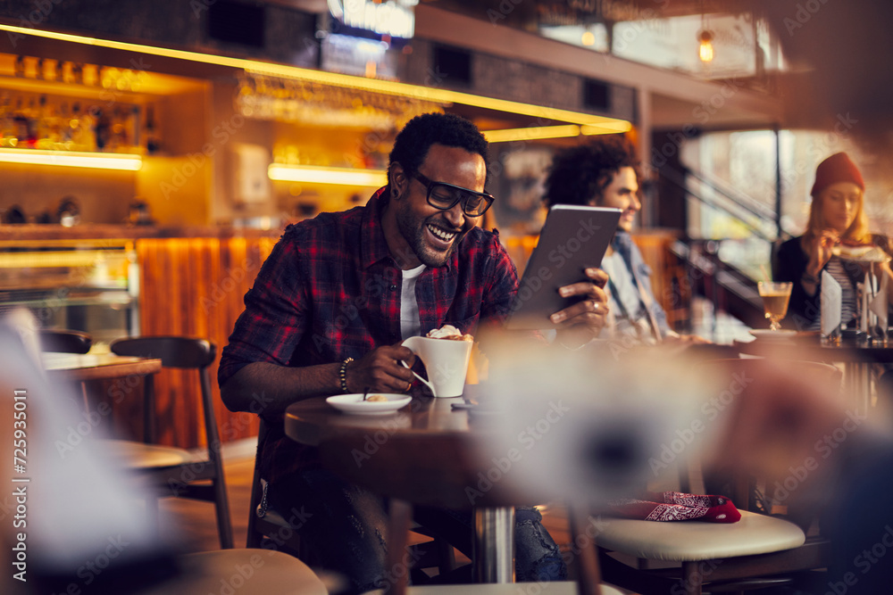 Young man using a digital tablet while enjoying a coffee at a cafe