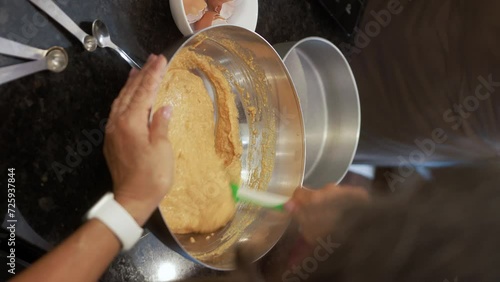 Experienced pastry chef expertly mixing a flavorful carrot cake composition in a metal bowl using a silicone spatula, showcasing precision and finesse, vertical video 
