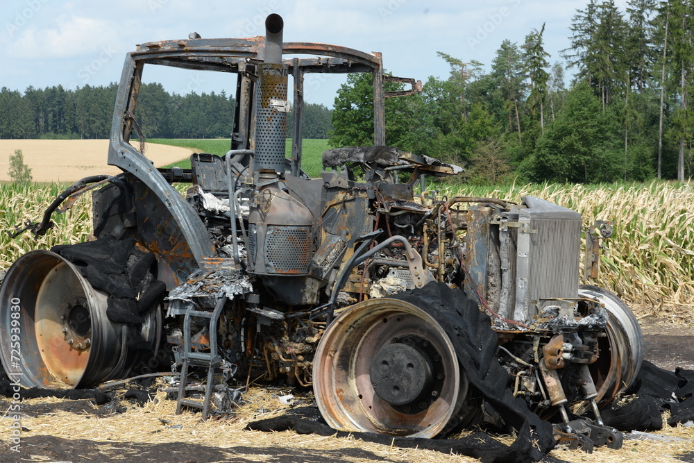 Große landwirtschaftliche Zugmaschine und Anhänger nach einem Brand auf einem Feld Große landwirtschaftliche Zugmaschine und Anhänger nach einem Brand auf einem Feld