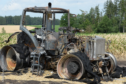 Große landwirtschaftliche Zugmaschine und Anhänger nach einem Brand auf einem Feld
