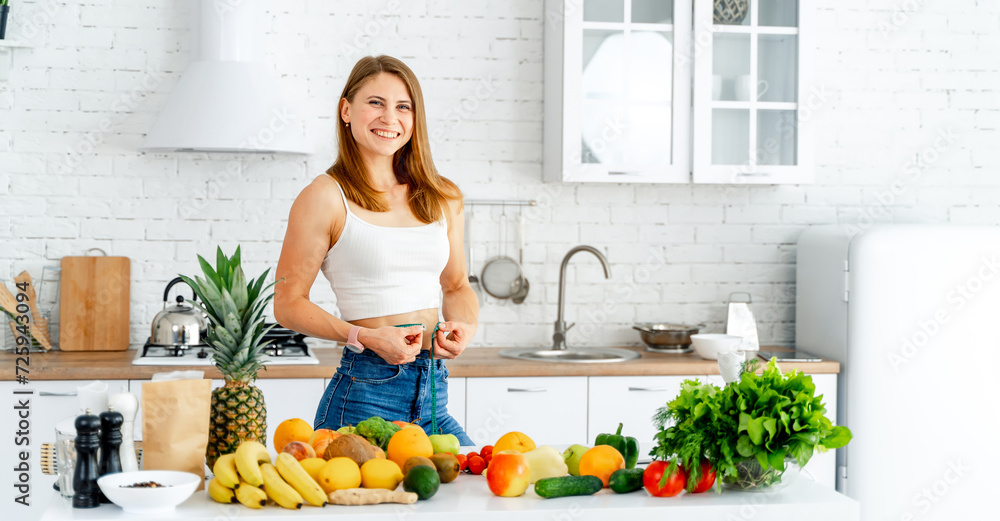 Young woman standing in the kitchen with fruits and vegetables Young woman standing in the kitchen with fruits and vegetables
