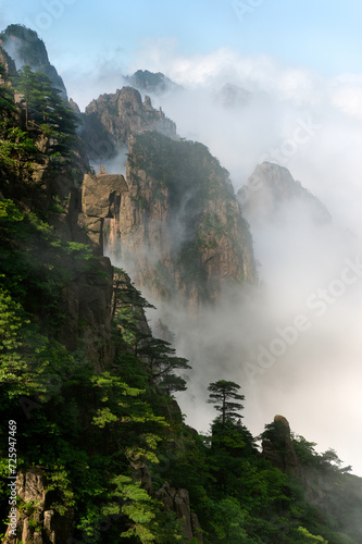Misty clouds hover around Cloud Dispersing Pavillion's Boot Rock in the Yellow Mountains of China.