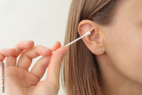 woman holds in hand disposable cotton bud, swab, stick. Girl cleans, washes her auricle earwax. Personal hygiene and care product. Prevention of ear diseases. Sulfur plug removal. photo