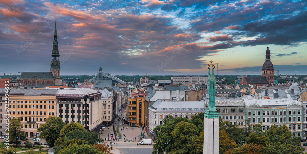 Naklejka premium Beautiful sunrise view over Riga by the statue of liberty - Milda in Latvia. The monument of freedom.