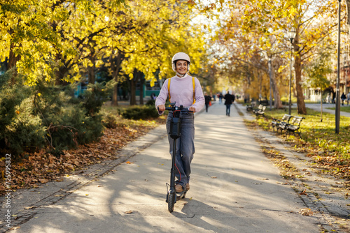 Front view of a trendy woman riding an electric scooter on city street.