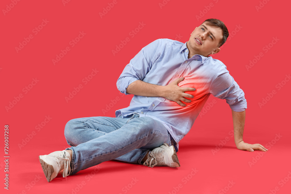 Young man having heart attack on red background Young man having heart attack on red background