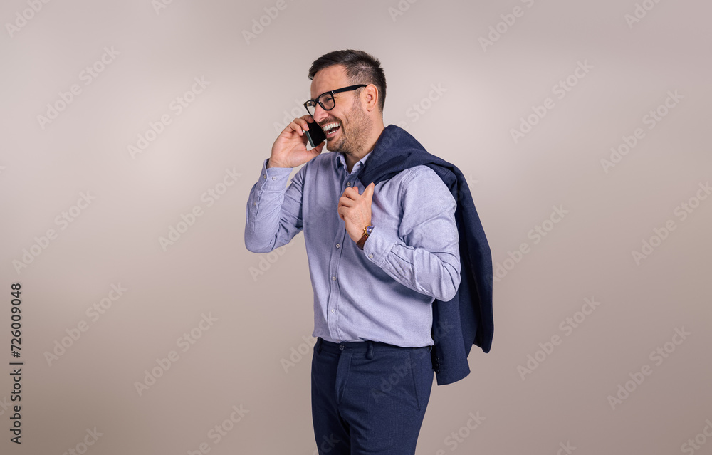 Happy young male CEO holding blazer and discussing ideas over mobile phone over white background Happy young male CEO holding blazer and discussing ideas over mobile phone over white background