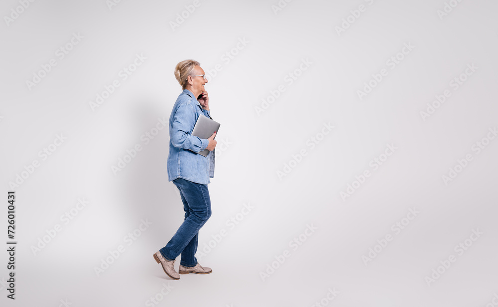 Side view of senior female freelancer with tablet talking over mobile phone on white background Side view of senior female freelancer with tablet talking over mobile phone on white background