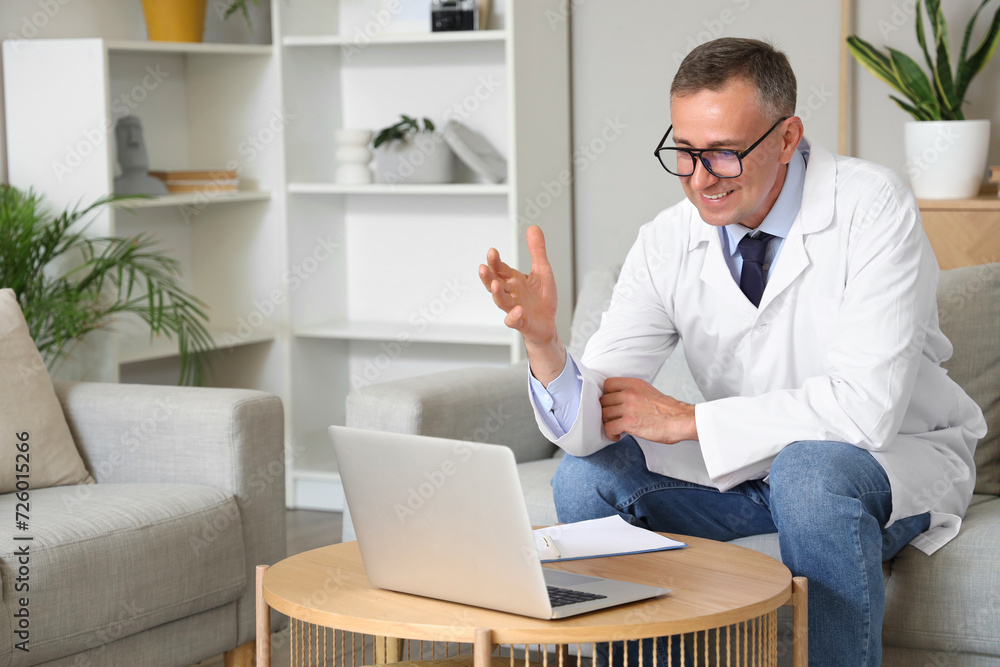 Mature doctor video chatting with patient on laptop at home Mature doctor video chatting with patient on laptop at home