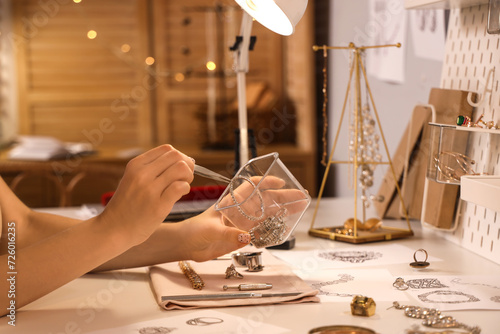 Female jeweler taking accessories from storage box in workshop photo