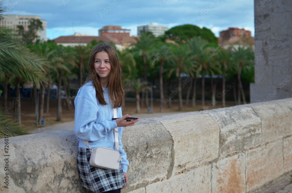 Young beautiful hipster woman using mobile phone in the city at sunset Young beautiful hipster woman using mobile phone in the city at sunset