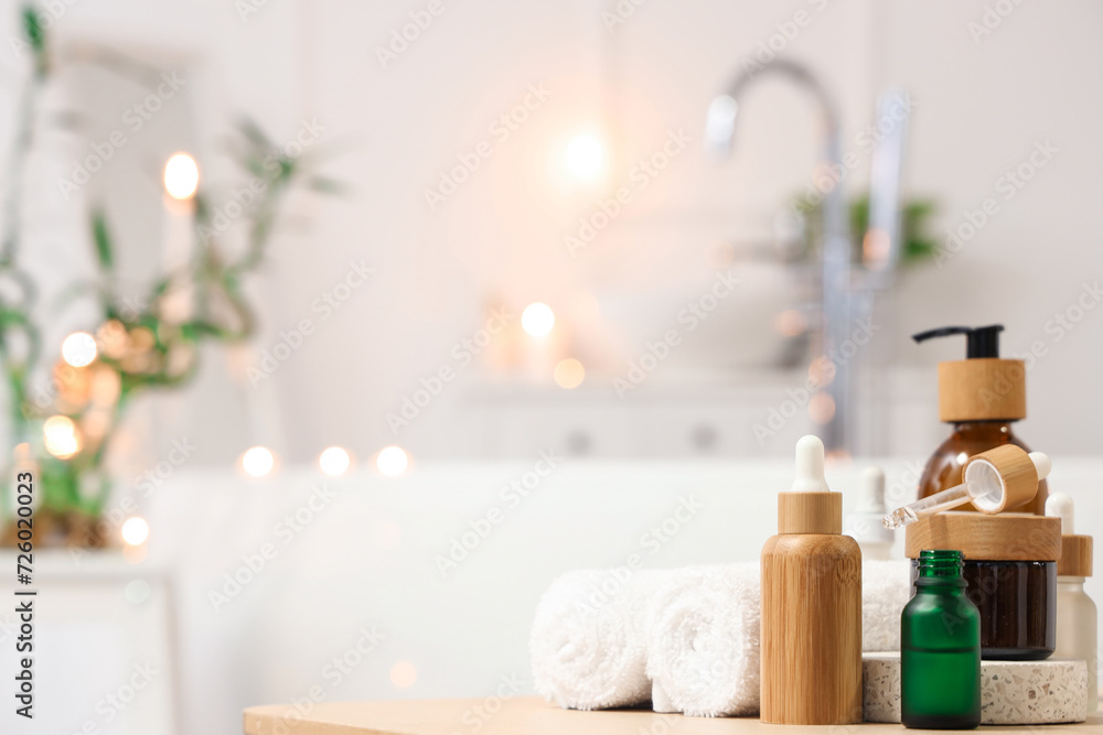 Bottles of skincare products with towels on table in bathroom, closeup