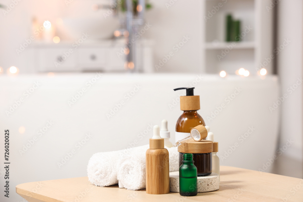 Bottles of skincare products with towels on table in bathroom, closeup