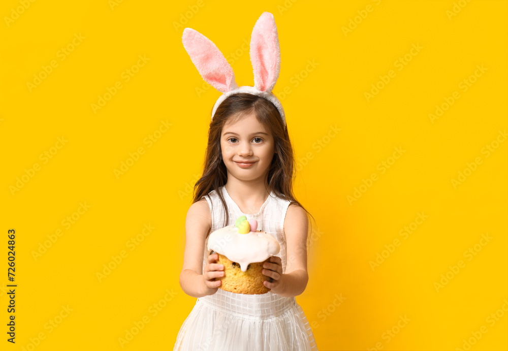 Cute little girl in bunny ears with Easter cake on yellow background Cute little girl in bunny ears with Easter cake on yellow background