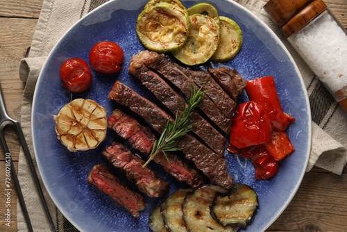 Delicious grilled beef steak with vegetables and spices on table, top view