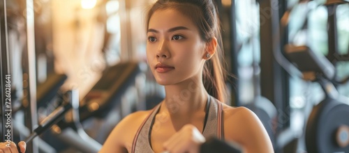 Asian woman exercises in gym to stay healthy with good diet, cardio decreases stress, cancer risk, and weight, while also strengthening muscles and heart.