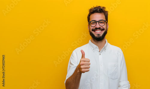 young happy man making thumbs up gesture on yellow background