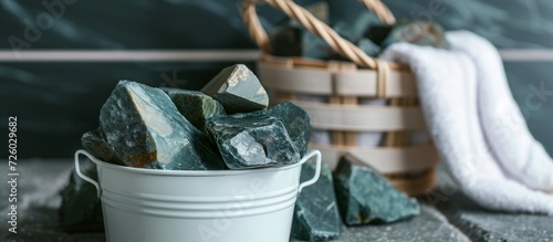 Serpentinite stones in white bucket, sauna background. photo