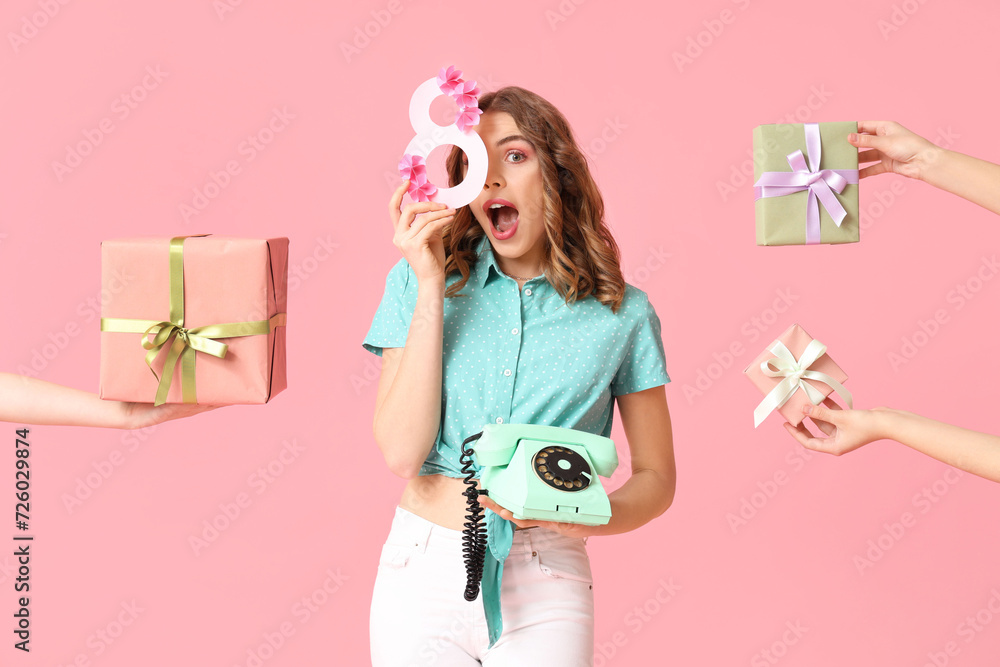 Young woman with retro telephone, figure 8 made of paper and hands holding gift boxes on pink background. International Women's Day - obrazy, fototapety, plakaty 